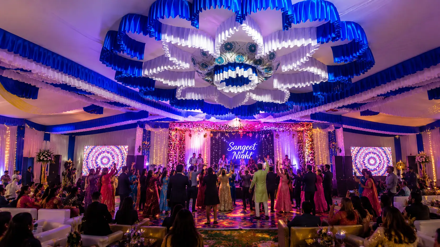 Sangeet night with an LED peacock ceiling installation and guests dancing under blue drapes